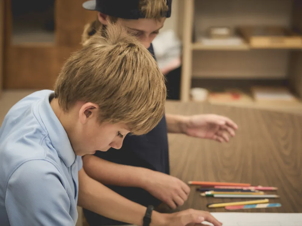 Two students working side by side with colored pencils in the classroom