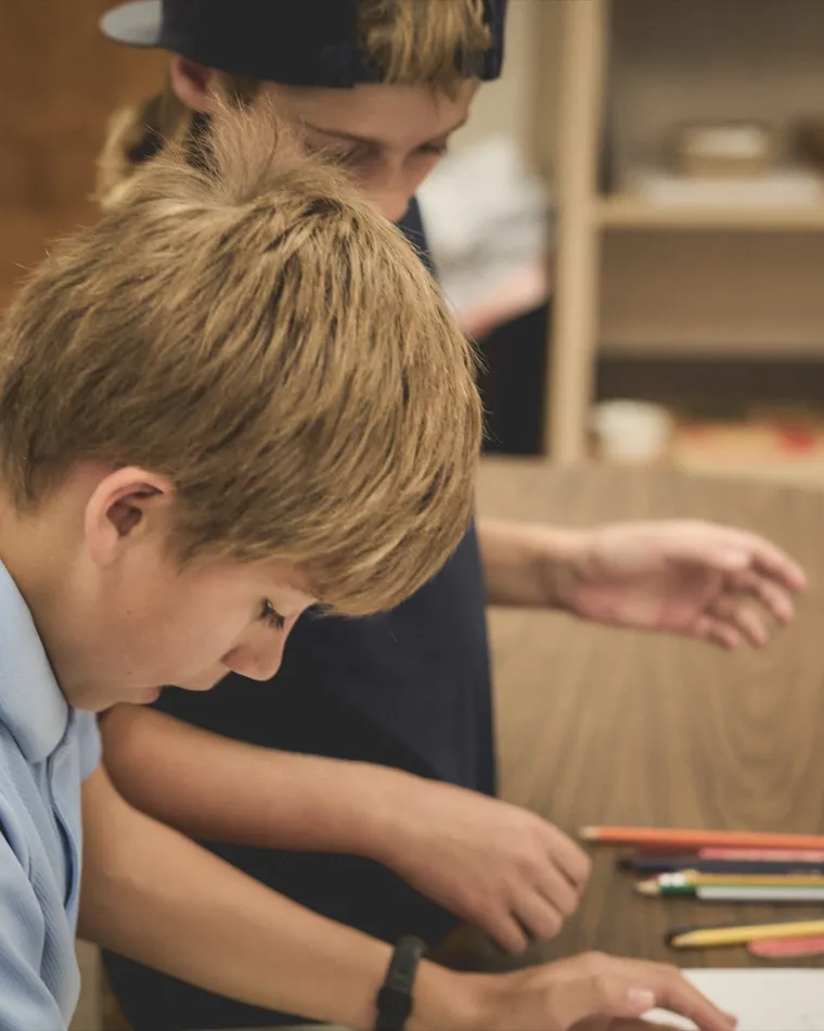 Two students drawing together at a classroom table