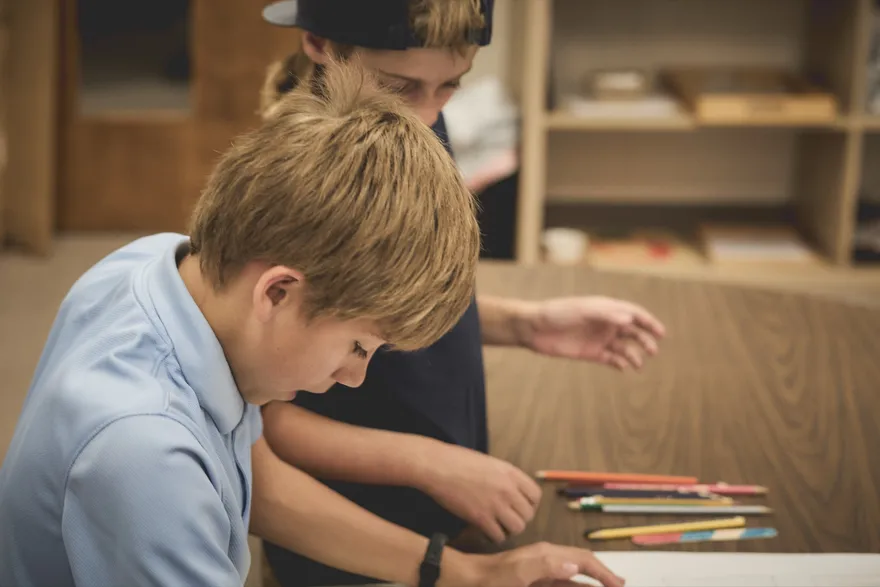 Two students drawing together at a classroom table